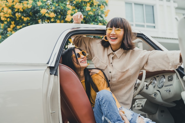 young asian woman friends smiling inside a car