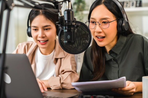 Young Asian woman in green shirts use microphones wear headphones with laptop record podcast interview for radio. Content creator concept.