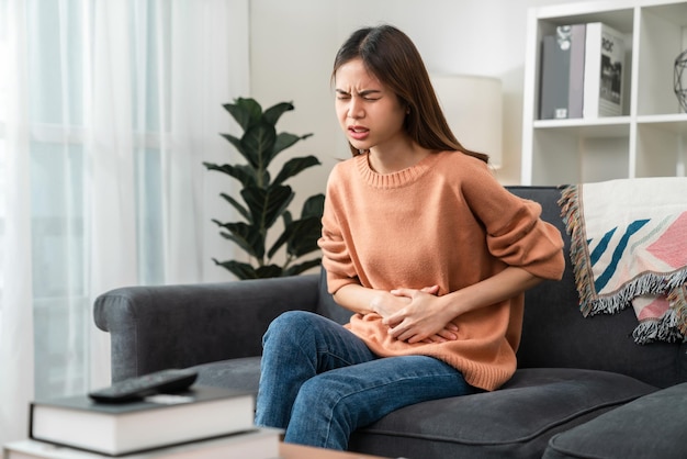 Young Asian woman hands holding the stomach and pain period cramps because having menstruation.