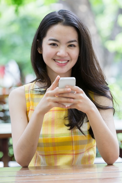 Young asian woman happily using a smart phone