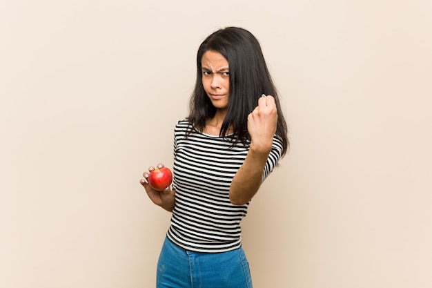 Young asian woman holding an apple showing fist