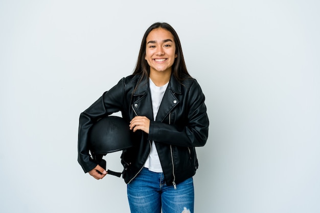 Young asian woman holding a motorbike helmet over isolated wall laughing and having fun.