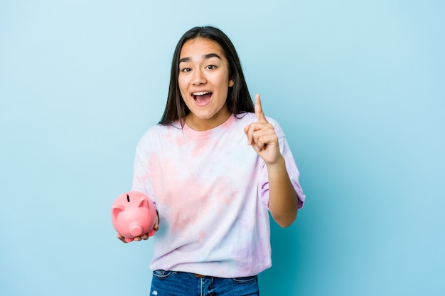 Young asian woman holding a pink bank over isolated wall having an idea, inspiration concept.