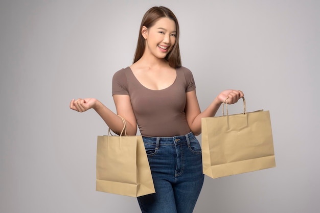 Young asian woman holding shopping bag over white background studio shopping and finance concept