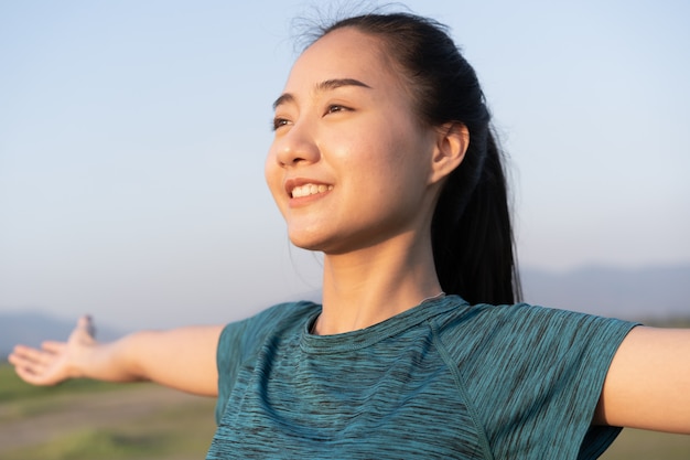 Young Asian woman is exercising with yoga while standing outdoor in summer