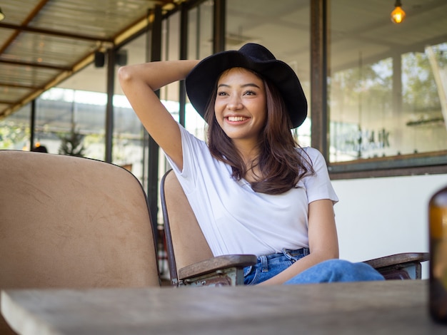 Young Asian woman is in a good mood sitting inside a cafe