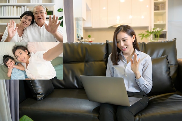 A young asian woman is using laptop computer to Video calling or Webcam to greeting her family ,  telecommunications technology , parenthood family concept