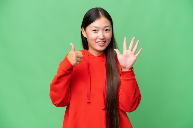 Young Asian woman over isolated background extending hands to the side for inviting to come