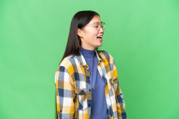 Young Asian woman over isolated chroma key background laughing in lateral position