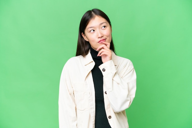 Young Asian woman over isolated chroma key background and looking up