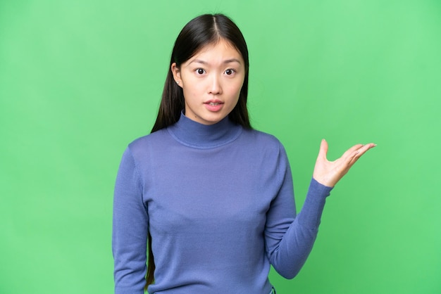 Young Asian woman over isolated chroma key background making doubts gesture