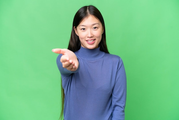 Young Asian woman over isolated chroma key background shaking hands for closing a good deal