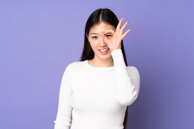 Young asian woman isolated on purple wall showing ok sign with fingers