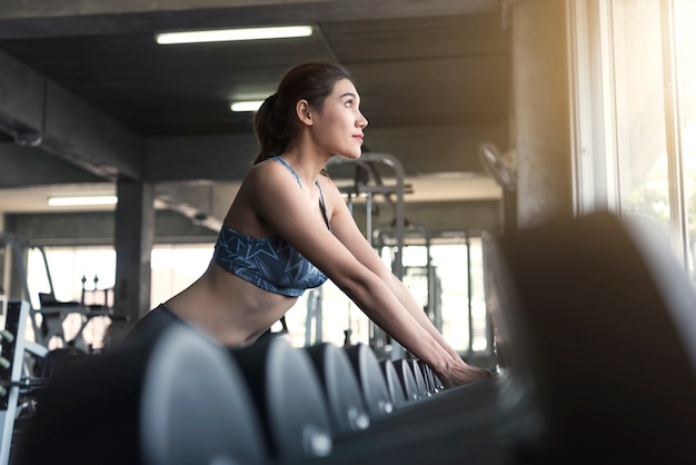 Young asian woman lifting dumbbells in gym. healthy lifestyle and workout motivation concept.