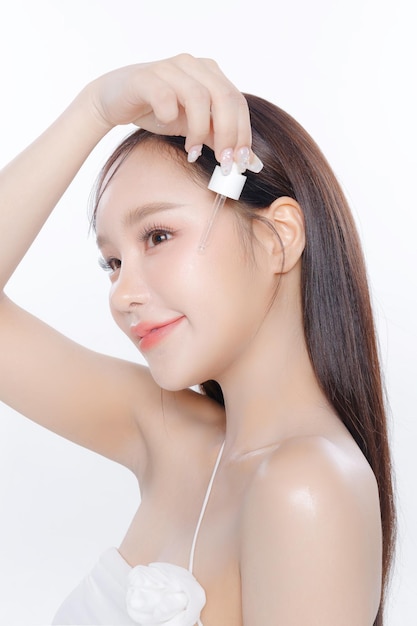 Young Asian woman long hair with clean fresh skin Korean makeup apply serum on white background Female model Face care Facial treatment Cosmetology beauty and spa Asian women portrait