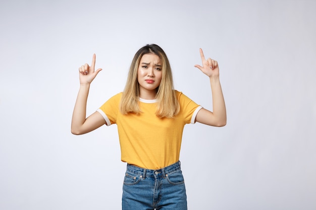 Young Asian woman looking angry and sad while pointing finger at camera