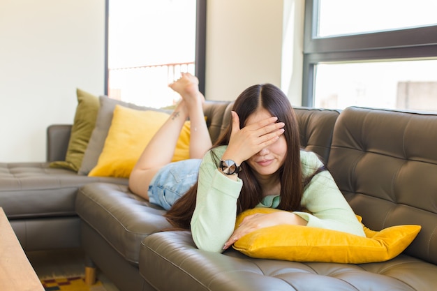 Young asian woman looking stressed, ashamed or upset, with a headache, covering face with hand