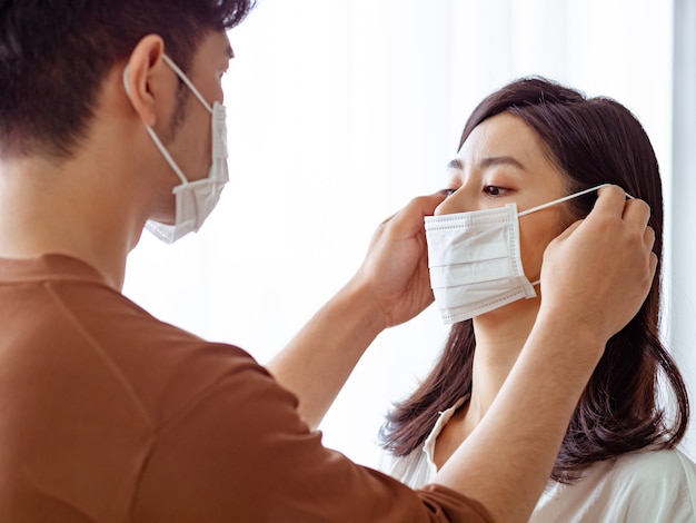 Young asian woman and man wearing Surgical mask at home