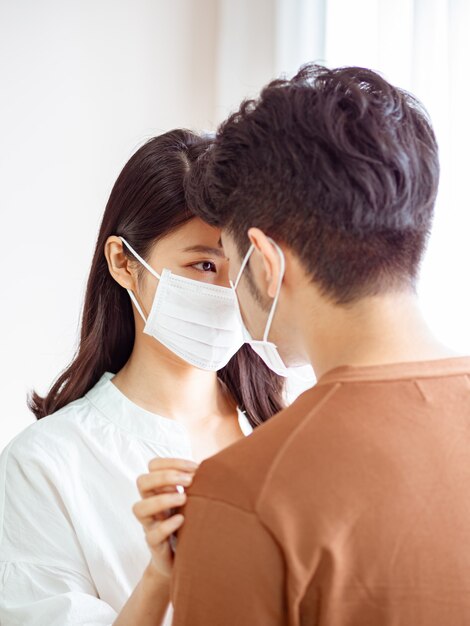 Young asian woman and man wearing Surgical mask at home