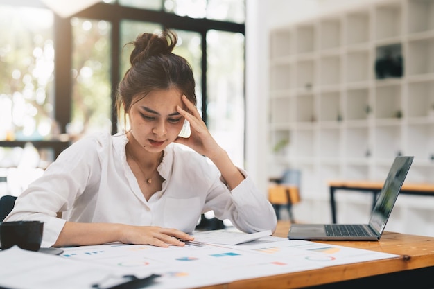 Young asian Woman Office Worker Uses Laptop Feels Sudden Burst of Pain Headache Migraine Overworked Accountant Feeling Project Pressure Stress Massages Her Head Temples