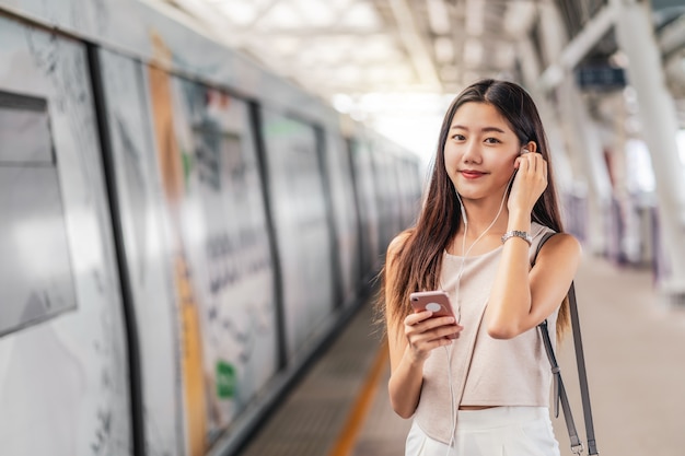 Young Asian woman passenger using and listening music