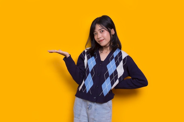 young asian woman pointing with fingers to different directions isolated on yellow background