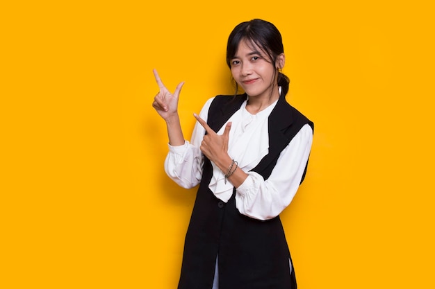 young asian woman pointing with fingers to different directions isolated on yellow background