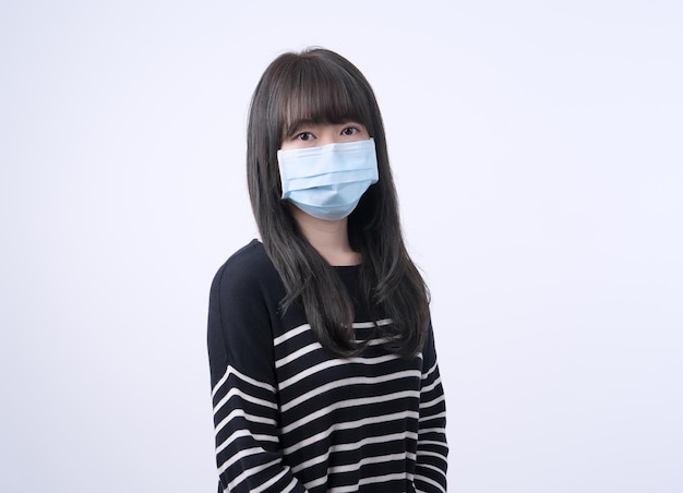 Young Asian woman portrait wearing a medical surgical blue face mask to prevent infection sick air pollution isolated on white background copy space close up cut out