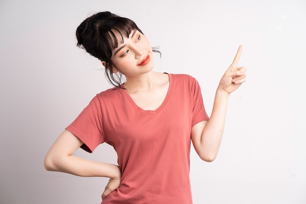 Young Asian woman posing on white, using finger to pointing and showing, hand gesture