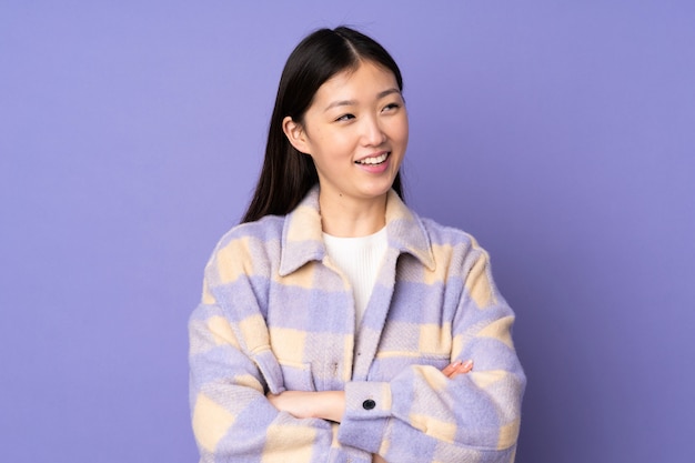 Young asian woman on purple wall happy and smiling