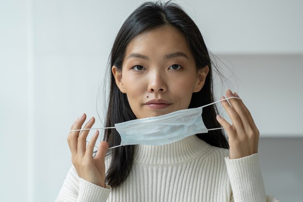 Young asian woman puts on a medical protective facial mask against virus and infection diseases