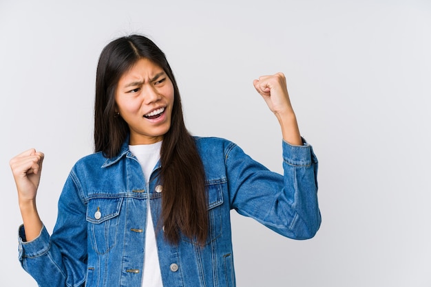 Young asian woman raising fist after a victory, winner concept.