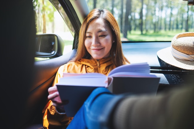 A young asian woman reading book while riding the car