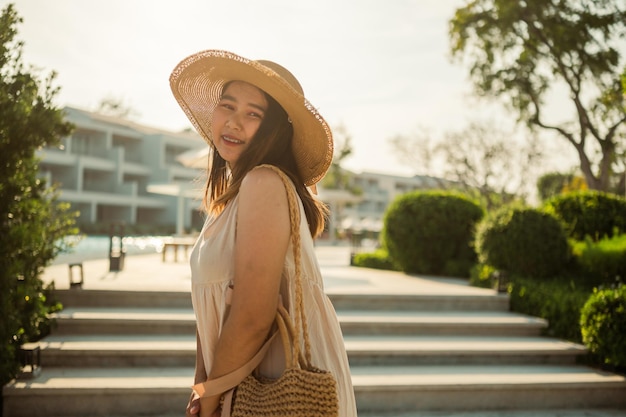 Young Asian woman relaxing beside the pool at luxury hotel travel and summer concept background