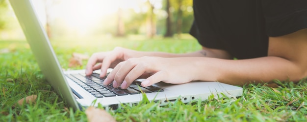 Young asian woman's legs on the green grass with open laptop