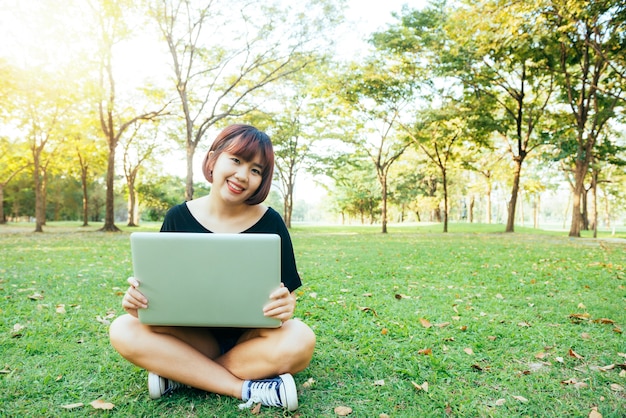 Young asian woman's legs on the green grass with open laptop