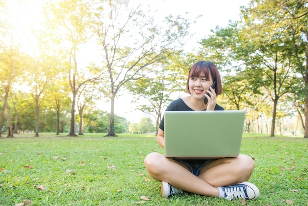 Young asian woman's legs on the green grass with open laptop