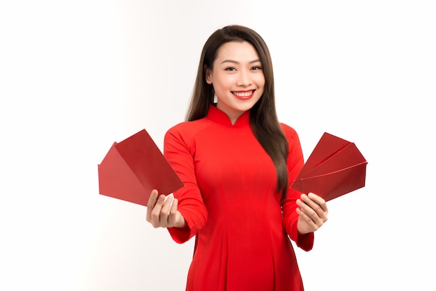 Young Asian woman showing red envelope for lunar new year while wearing Ao Dai over white.