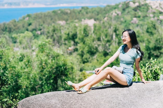 Young Asian woman sitting on a rock in summer