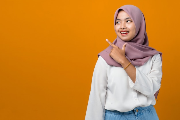 Young asian woman smiling and pointing to empty space