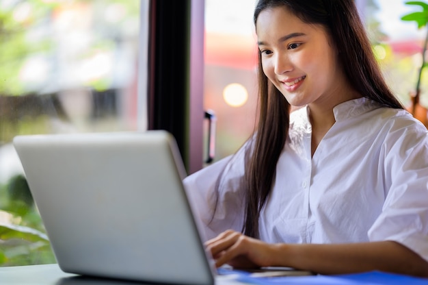 Young asian woman smiling and using laptop