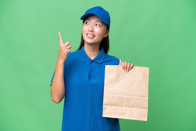 Young Asian woman taking a bag of takeaway food over isolated background pointing up a great idea