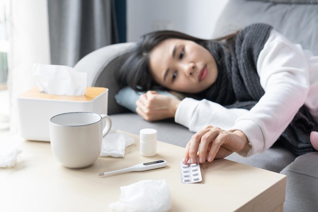 Young Asian woman taking pills for flu at home Millennial female have medicines at home Healthcare concept Closeup copy space