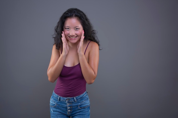 Young asian woman in tank top with funny expression isolated from the background