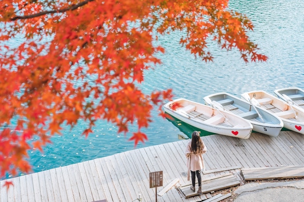 Young asian woman traveler enjoying the view of Red maple leaf on Goshikinuma or Five Colored Pond in autumn in Fukushima prefecture, Japan