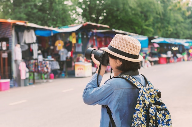 Young asian woman traveler taking photo on street market 