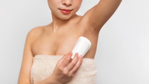 Young asian woman using applying deodorant in bathroom