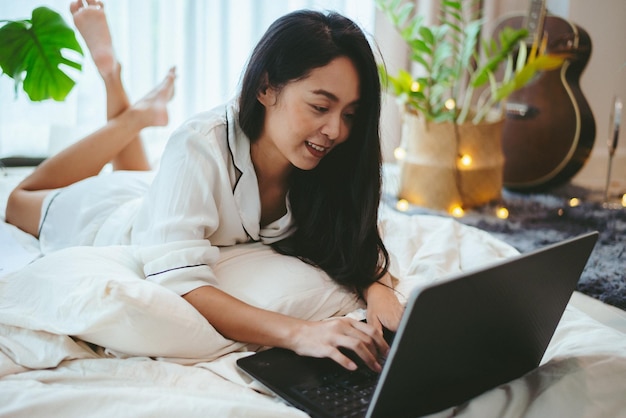 Young Asian woman using laptop computer to business online work female freelance working from home by using internet cyberspace communication technology for businesswoman job