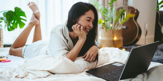 Young Asian woman using laptop computer to business online work female freelance working from home by using internet cyberspace communication technology for businesswoman job