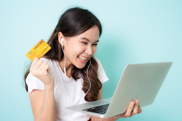 Young asian woman using laptop and showing credit card